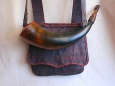 Randy Hedden Bison & Pig ComboThis eastern style pouch, made from veg tanned pig, measures 8" deep, 8" wide at the bottom and tapers to 6-3/4" wide at the top.  It has a 1" wide gusset at the bottom and a small hanging ball pouch.  The 1-1/2" wide strap is adjustable by means of a brass harness buckle.  The eastern style bison horn powder horn measures 14-1/2" around the outside curve and 2-7/8" diameter at the butt plug and features an applied horn spout..  The butt plug was made from a cherry log salvaged from a log cabin built in 1805.  The horn is one of those strange bison horns that  show a lot of white on the horn.  The set has a river cane powder measure  and a wound brass vent pick.Photo by Randy Hedden